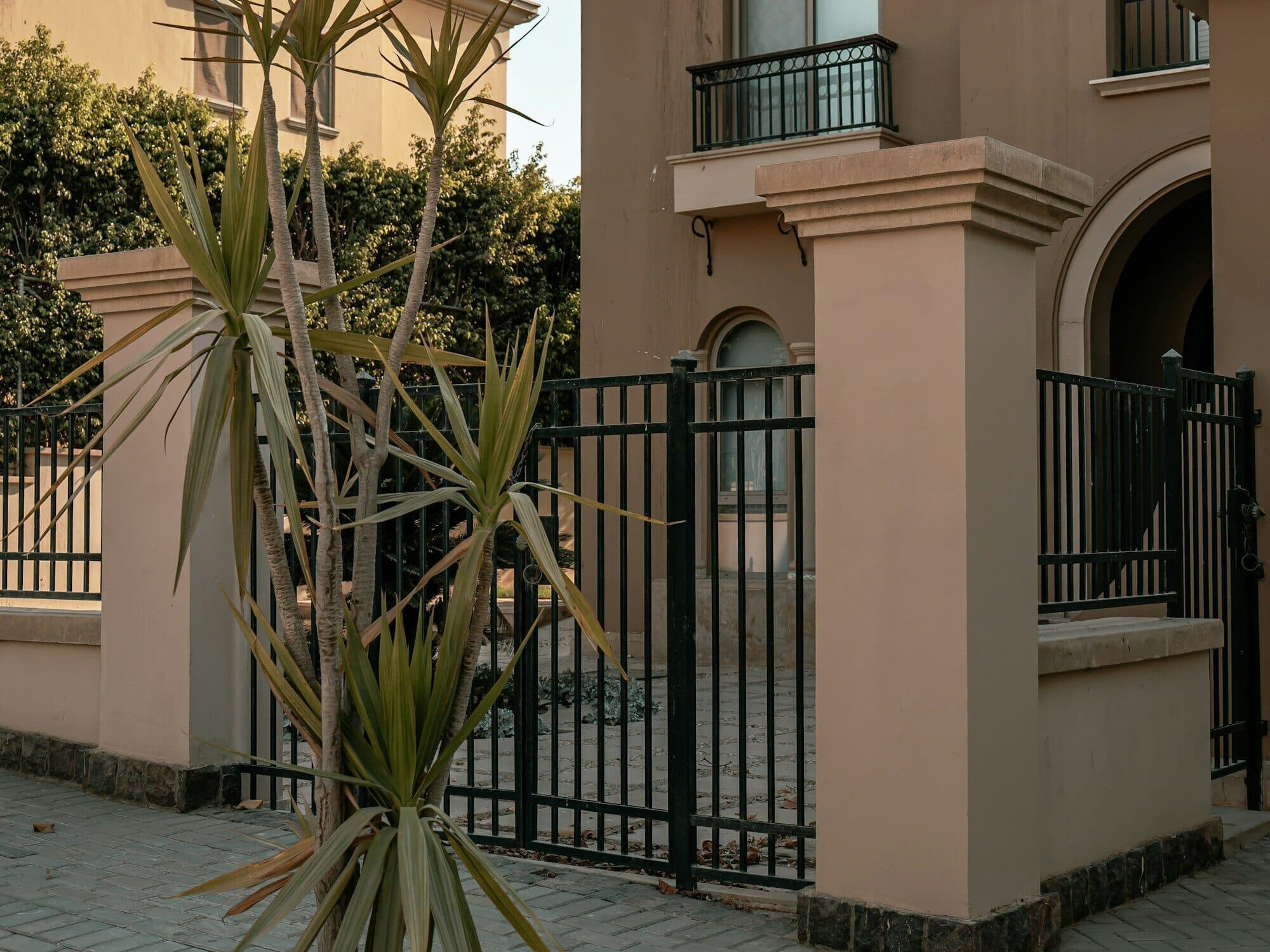 Black vertical-bar metal fence and gate in front of a house